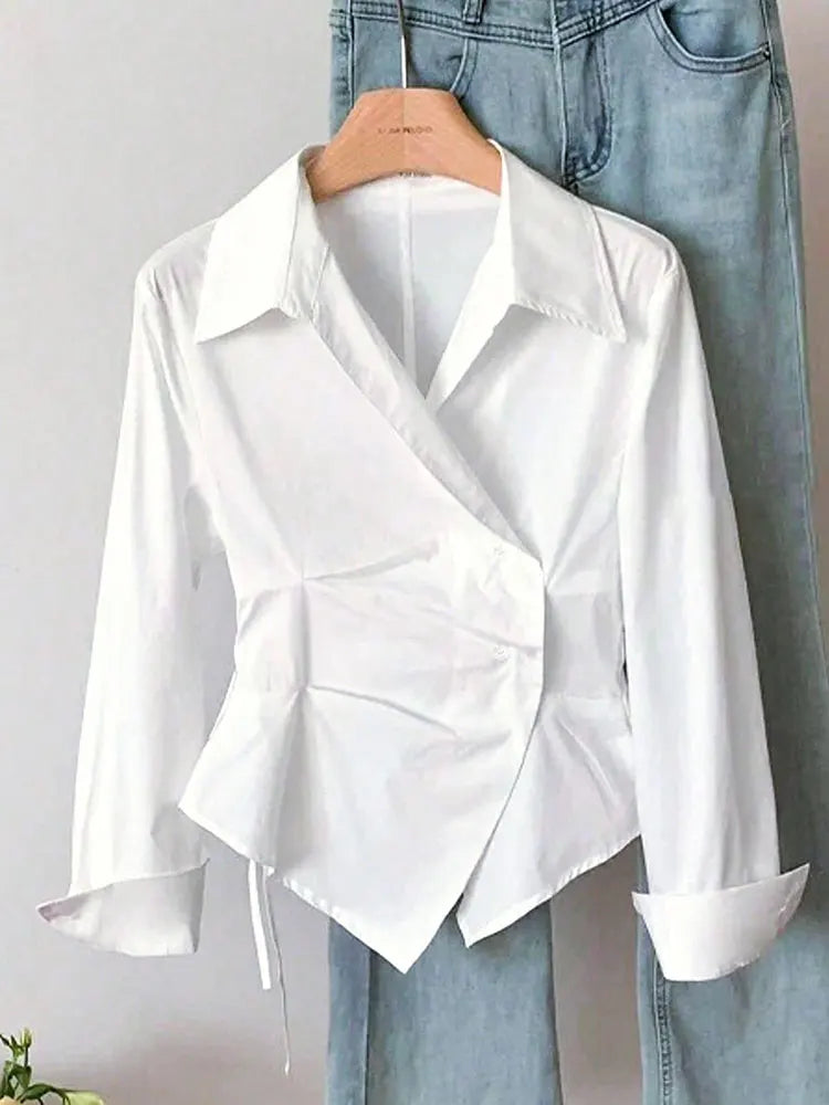 White blouse with a unique design on a hanger against a light gray background