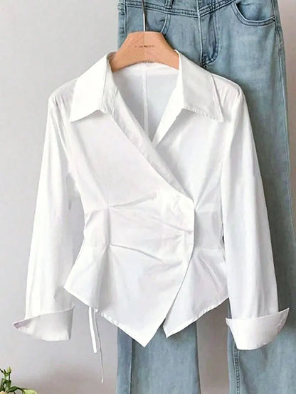 White blouse with a unique design on a hanger against a light gray background