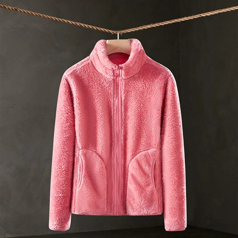 Pink fleece jacket hanging on a clothesline against a dark background