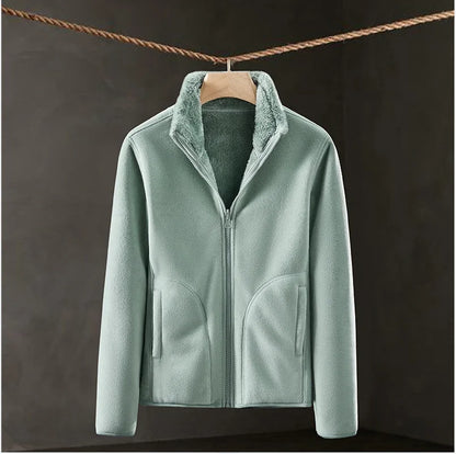 Light green fleece jacket hanging on a wooden hanger against a dark background