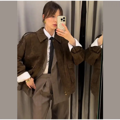 Person taking a mirror selfie wearing a brown jacket and gray pants.