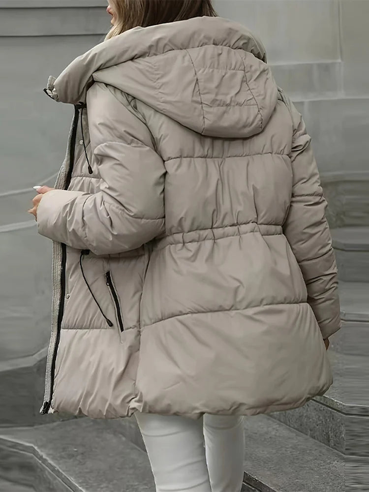 Person wearing a beige puffer jacket on a neutral background