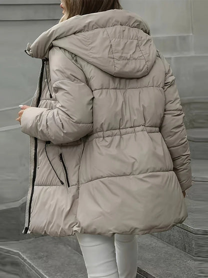 Person wearing a beige puffer jacket on a neutral background
