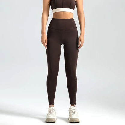 Person wearing brown leggings and a white sports bra on a light gray background