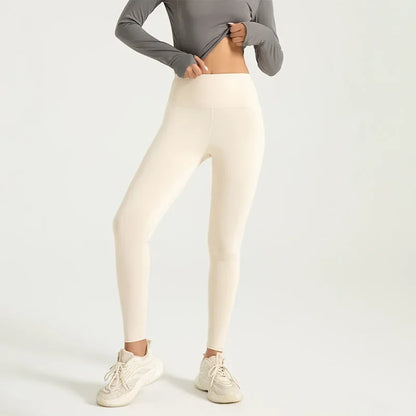 Person wearing cream leggings with a plain background