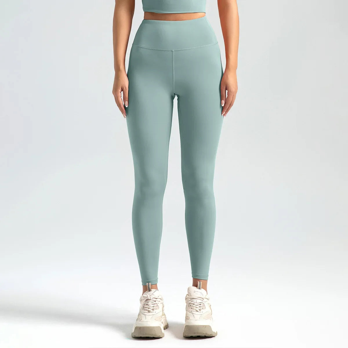 Person wearing light green leggings and a matching top on a white background