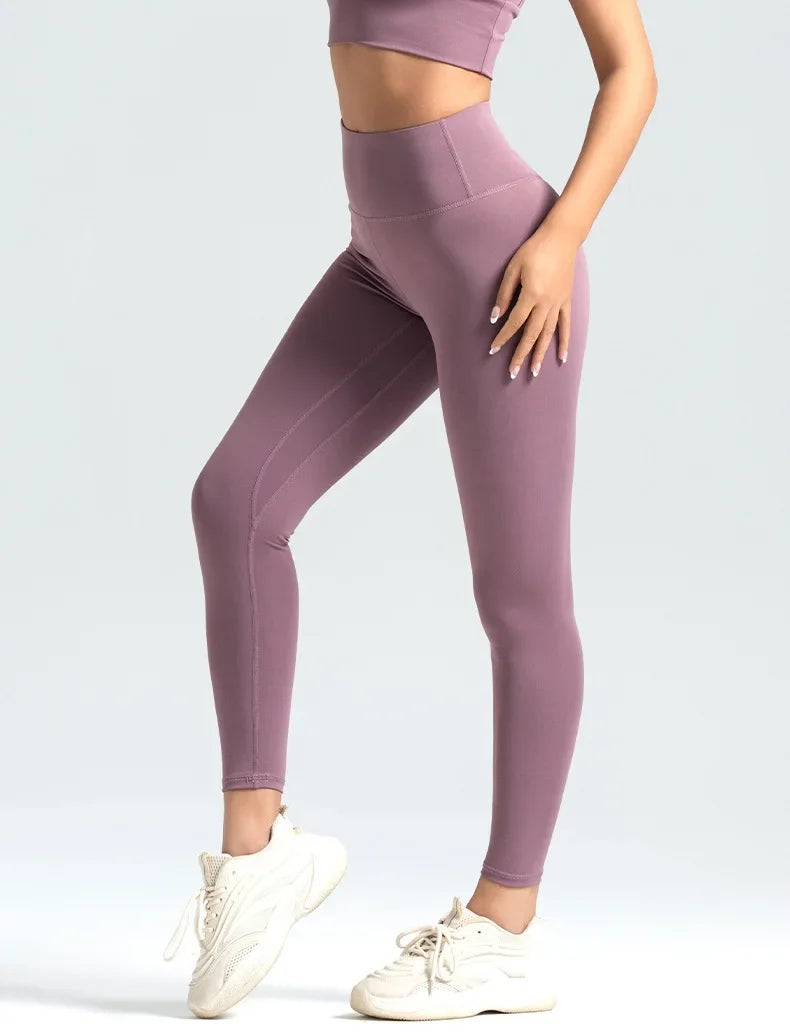 Person wearing mauve leggings and a matching top on a white background
