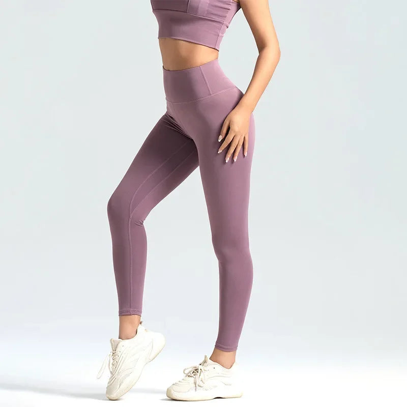 Person wearing mauve leggings and top on a light gray background