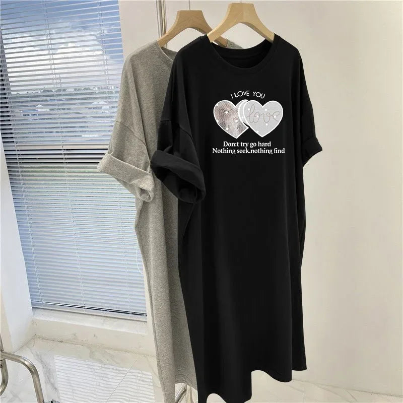 Black t-shirt with heart designs and text on a hanger against a window background