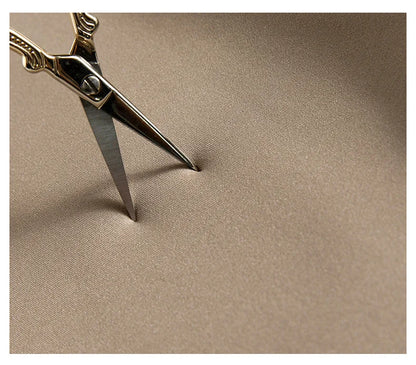 Pair of gold scissors on a beige fabric background