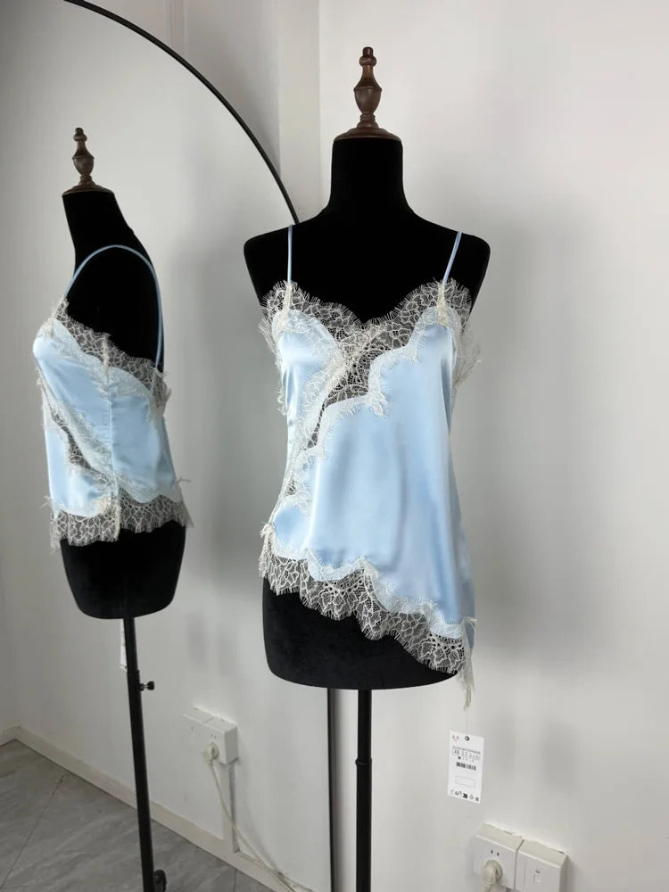 Light blue lace camisoles on black mannequins against a white wall.