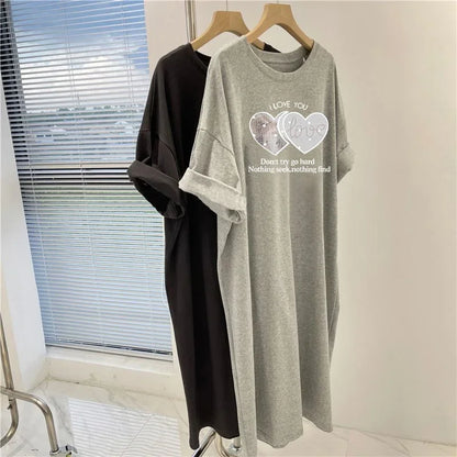 Two t-shirts, one black and one gray with text and heart designs, hanging on a rack.