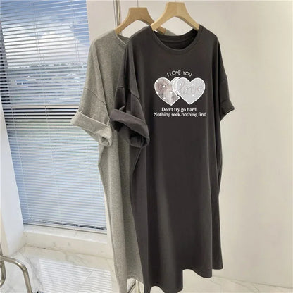 Two t-shirts, one gray and one black with a graphic design, hanging on wooden hangers against a neutral wall.