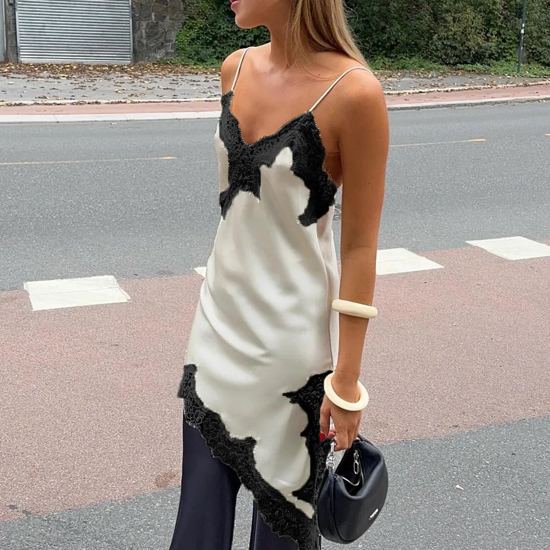 Woman wearing a black and white dress with lace details on a street.