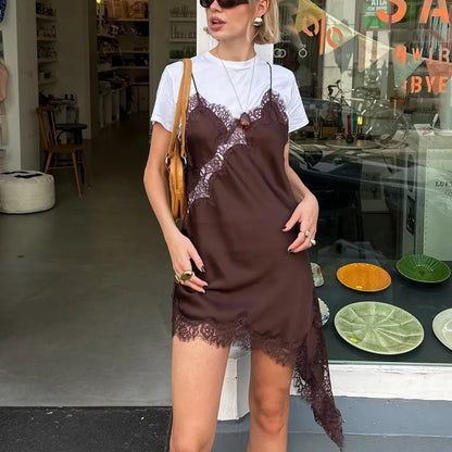 Woman wearing a brown slip dress over a white shirt in an indoor setting with decor elements.