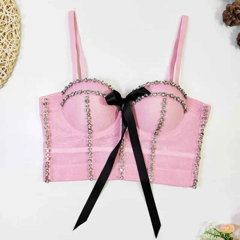 Pink bra with decorative chain and black ribbon on a white background