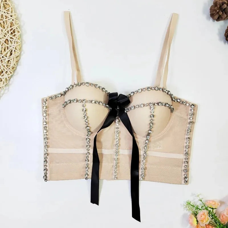 Beige bra with decorative black ribbon and rhinestones on a white background
