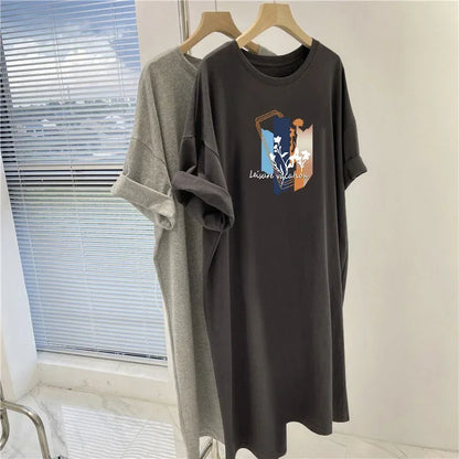 Two t-shirts, one gray and one black with a graphic design, hanging on wooden hangers against a neutral wall.