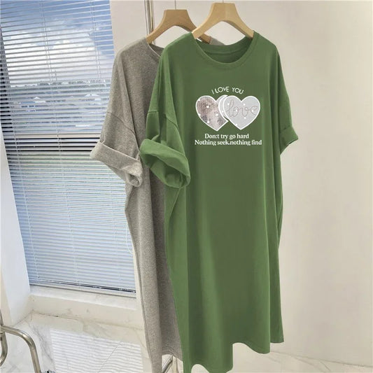 Green dress with printed design on a hanger against a window background