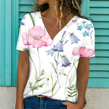 Woman wearing a white V-neck t-shirt with colorful floral designs against a teal background.