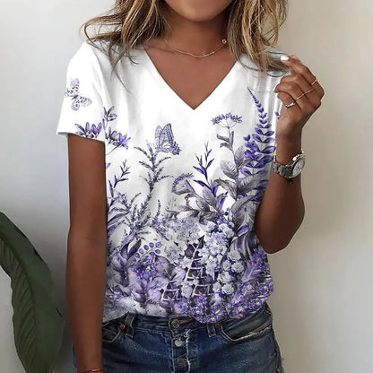 Person wearing a white t-shirt with purple floral design, holding a glass.
