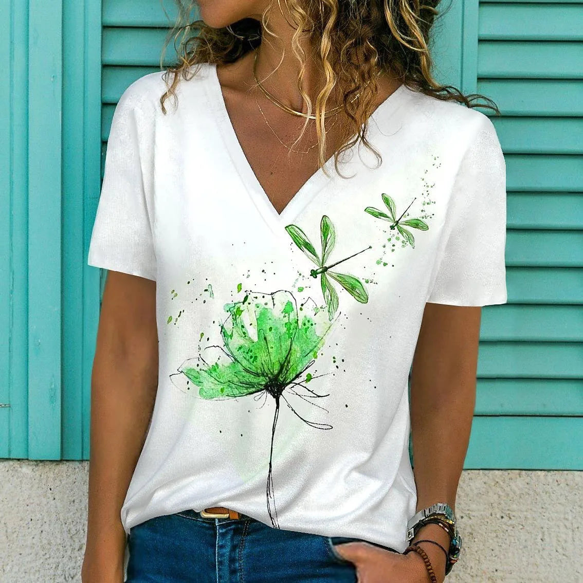 Person wearing a white t-shirt with green floral designs against a teal background