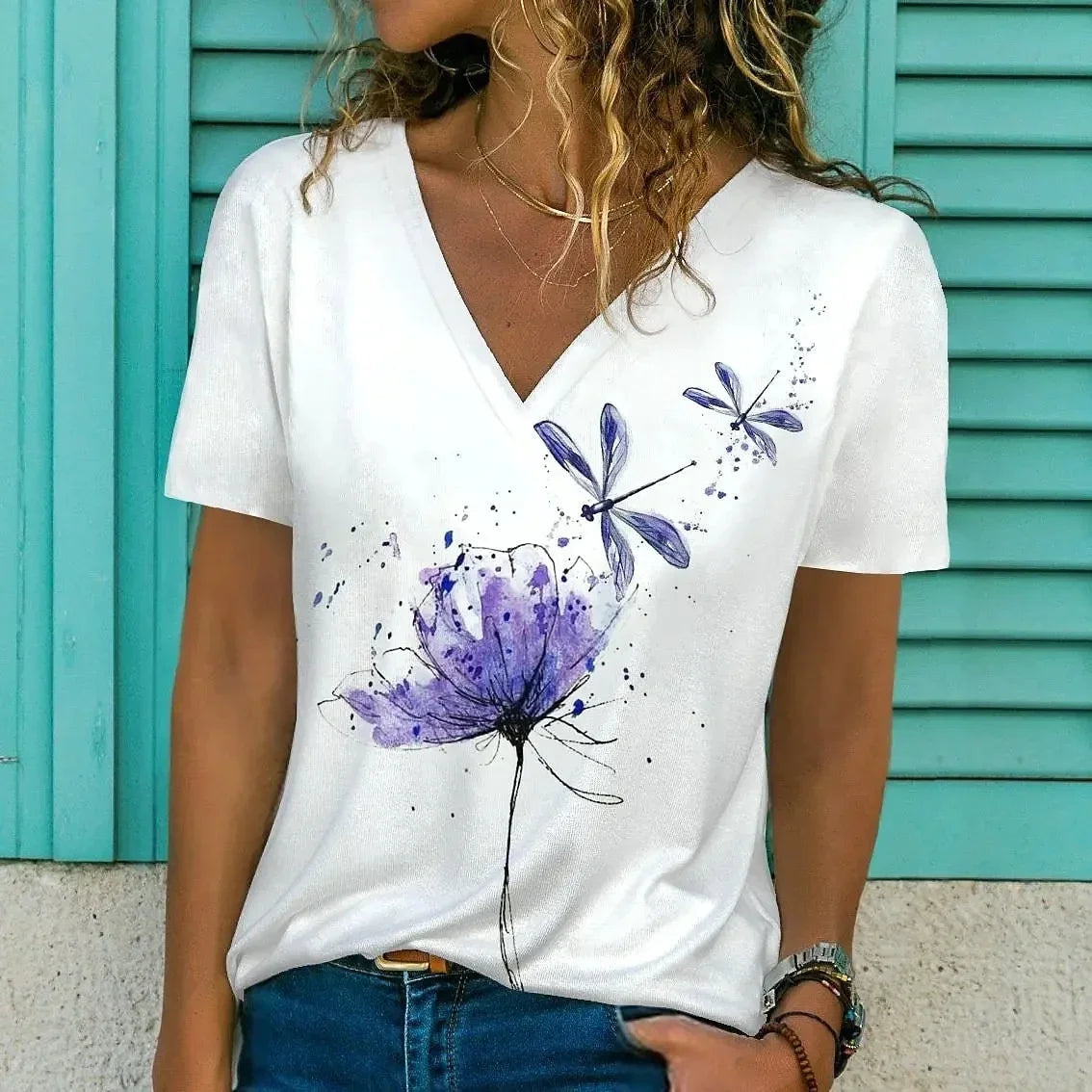 Person wearing a white t-shirt with purple floral designs against a teal background