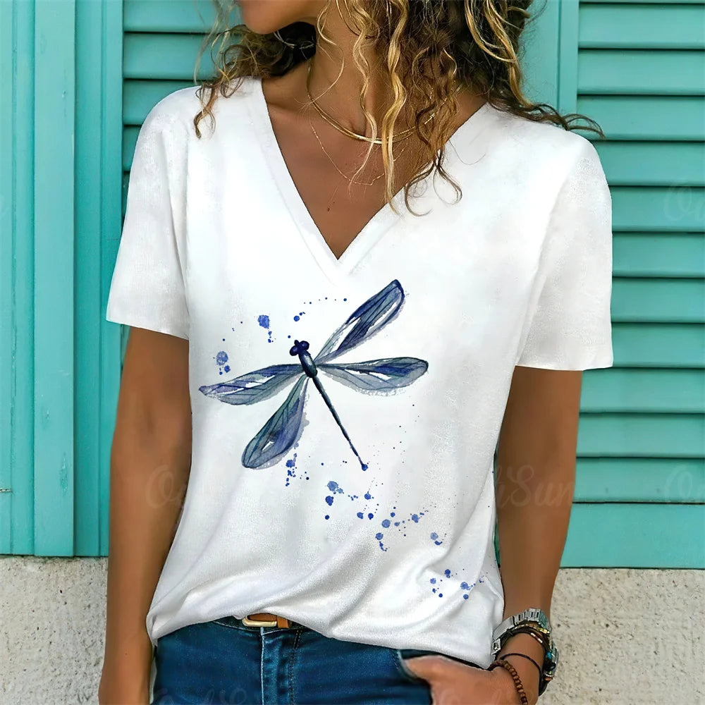 Person wearing a white t-shirt with a blue dragonfly design against a turquoise background