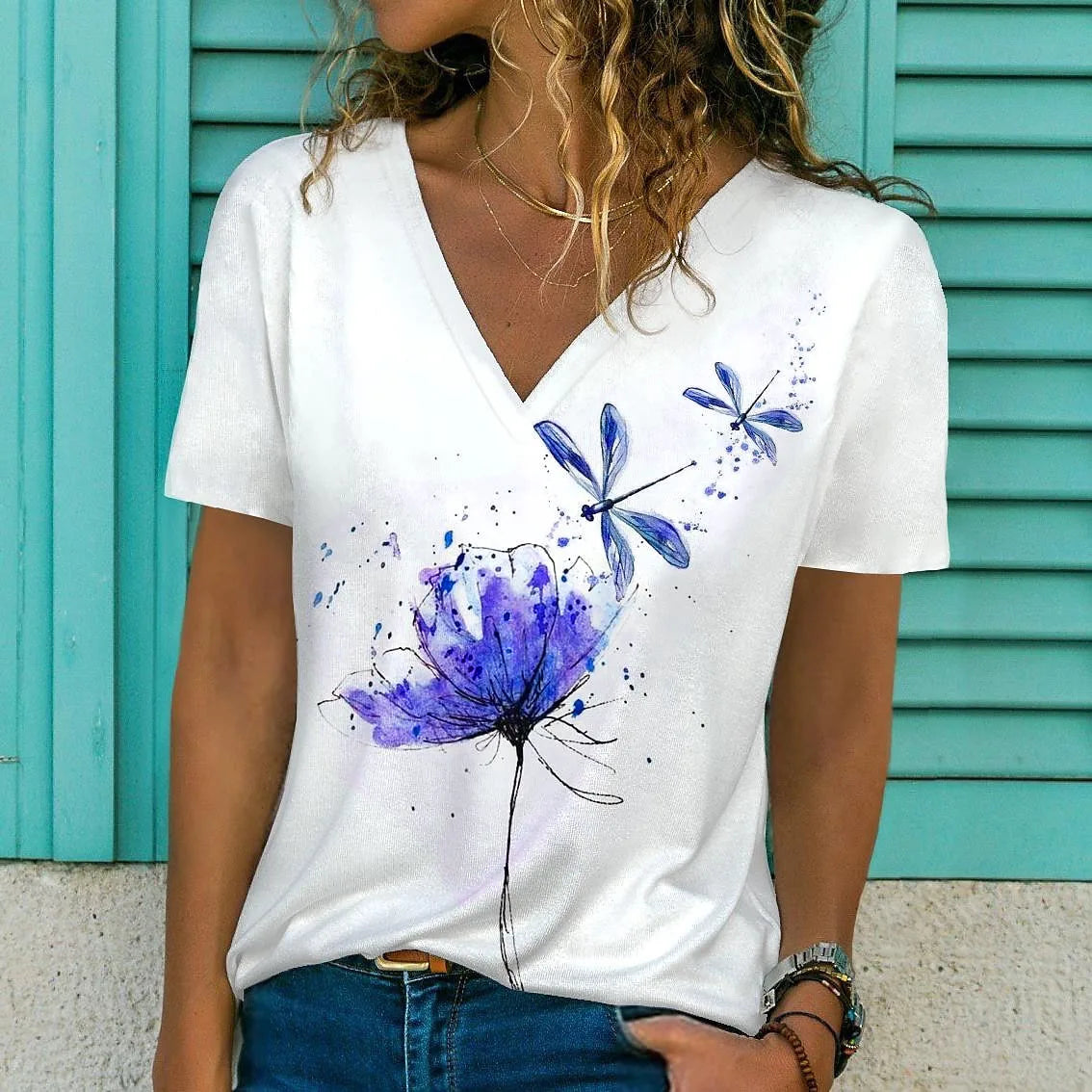 White t-shirt with blue floral designs worn by a person against a teal background
