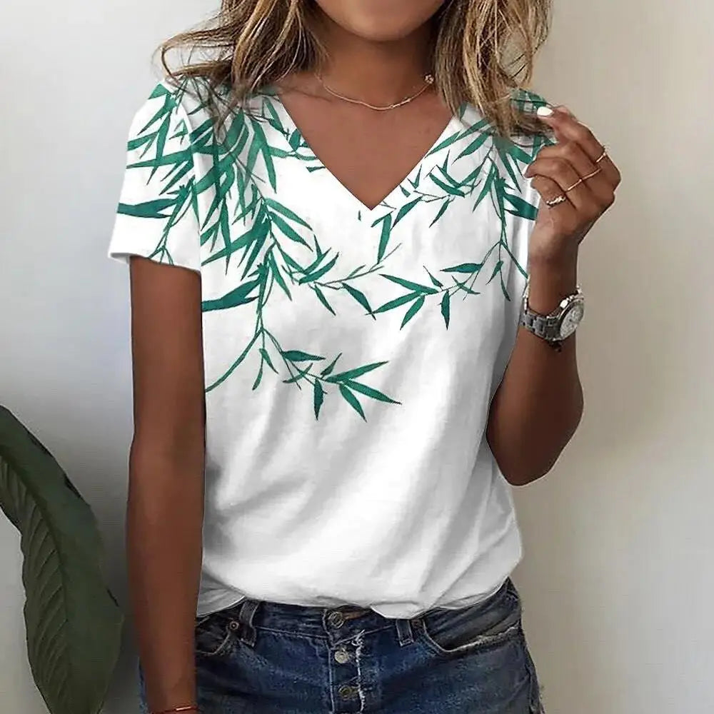 Person wearing a white t-shirt with green leaf pattern and blue jeans.