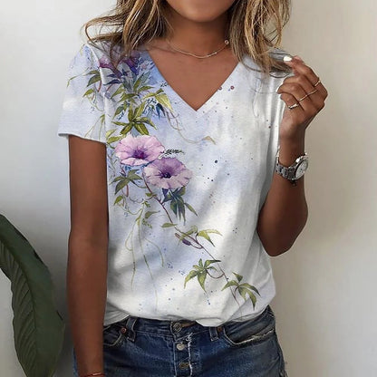 Person wearing a white t-shirt with floral designs, holding a phone.