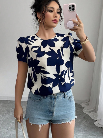 Woman taking a mirror selfie wearing a navy floral top and denim shorts.