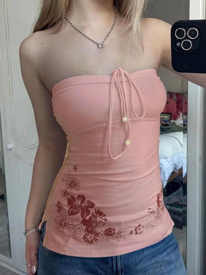 Person wearing a pink strapless top with floral embroidery, standing indoors.