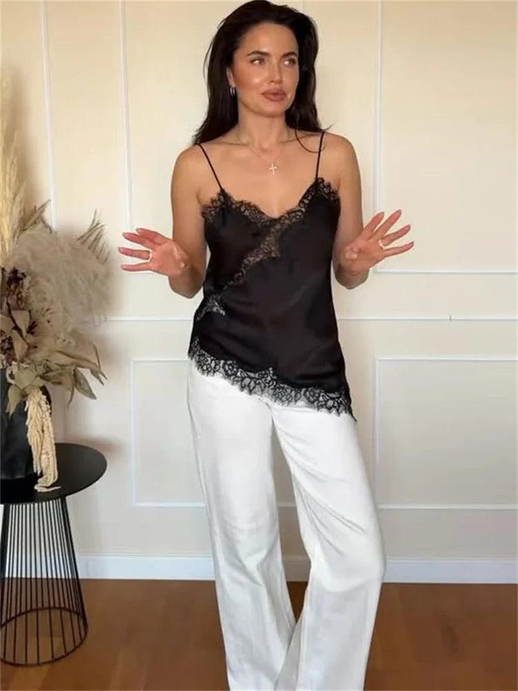 Woman wearing a black lace top and white pants in a room with decorative elements.