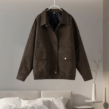 Brown jacket hanging on a hanger against a neutral wall.