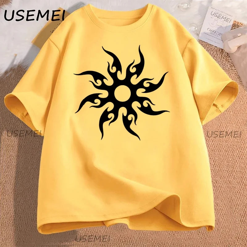 Yellow t-shirt with black tribal sun design on a textured surface