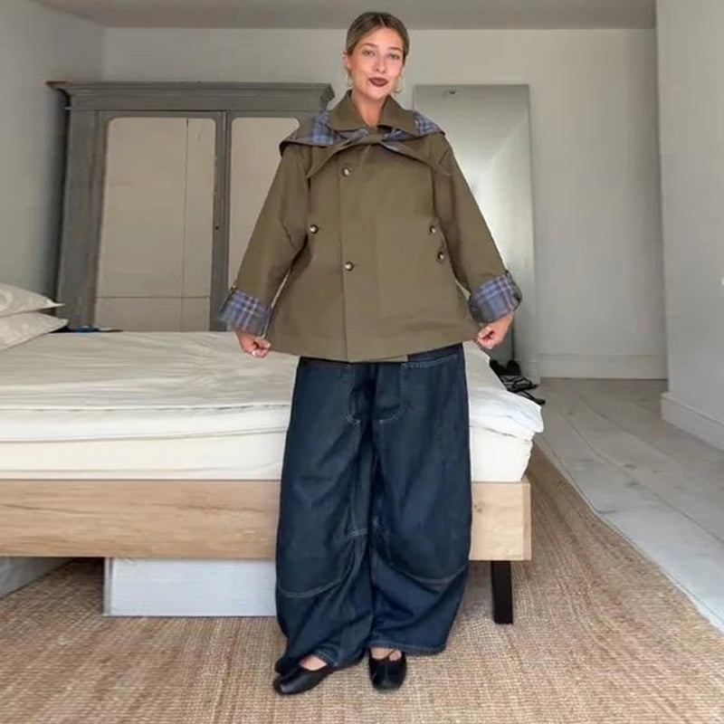 Person wearing a green coat with plaid accents in a bedroom setting