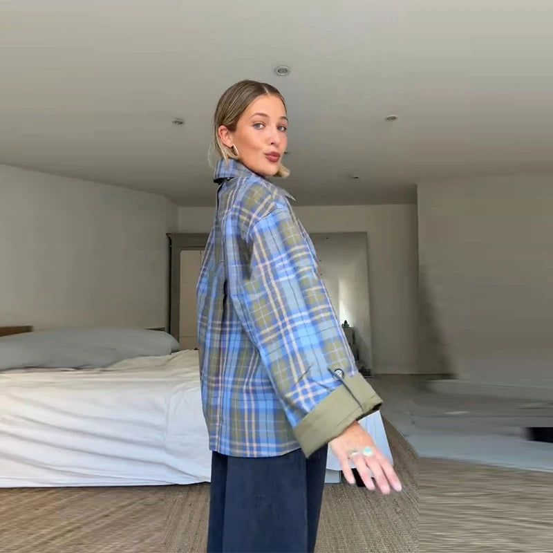 Woman wearing a blue plaid shirt in a minimalistic room.