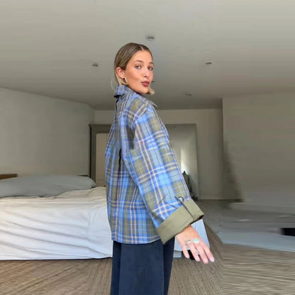 Woman wearing a blue plaid shirt in a minimalistic room.