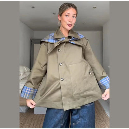 Woman wearing a green coat with plaid lining in an indoor setting