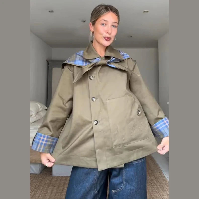 Woman wearing a green coat with plaid lining in an indoor setting