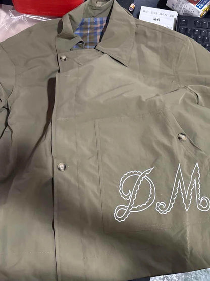 Green jacket with 'DM' logo on a surface