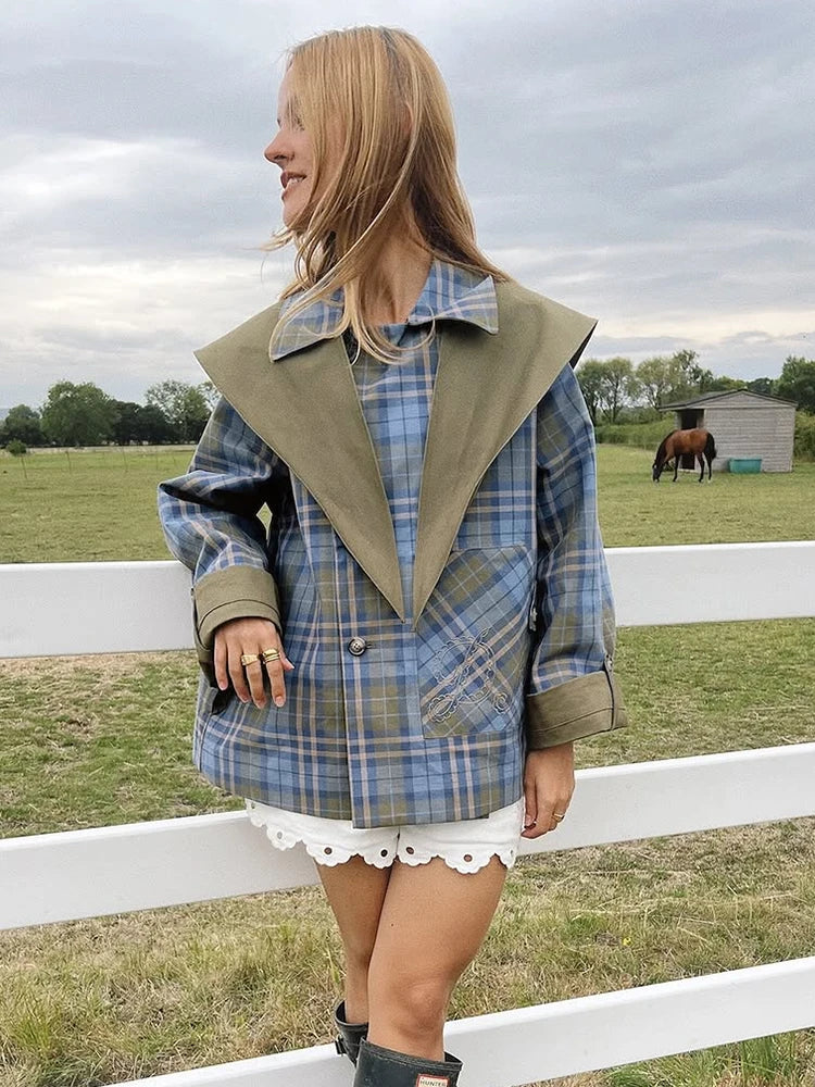 Woman wearing a plaid jacket with a horse and field in the background