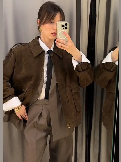 Person taking a mirror selfie wearing a brown jacket and gray pants.