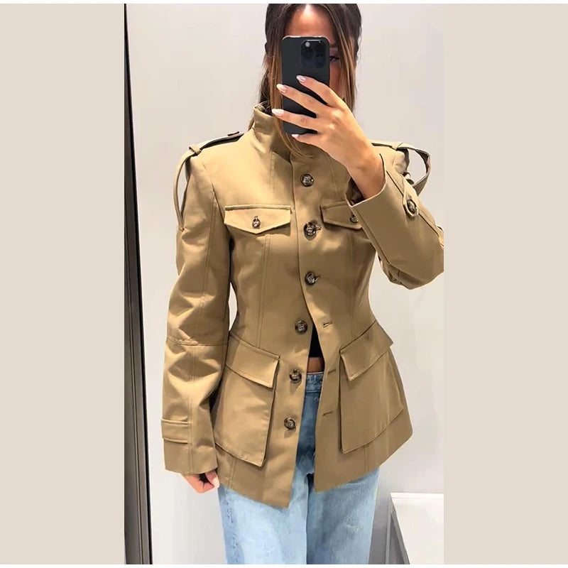 Person wearing a beige trench coat taking a mirror selfie.