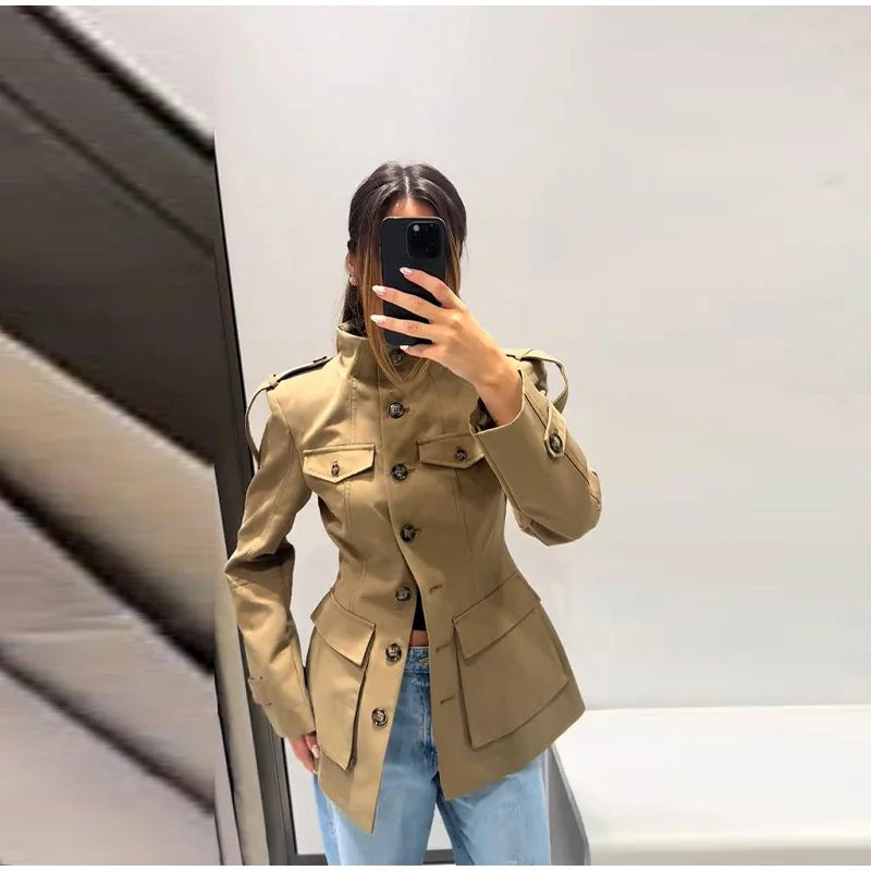 Person wearing a beige trench coat taking a mirror selfie.
