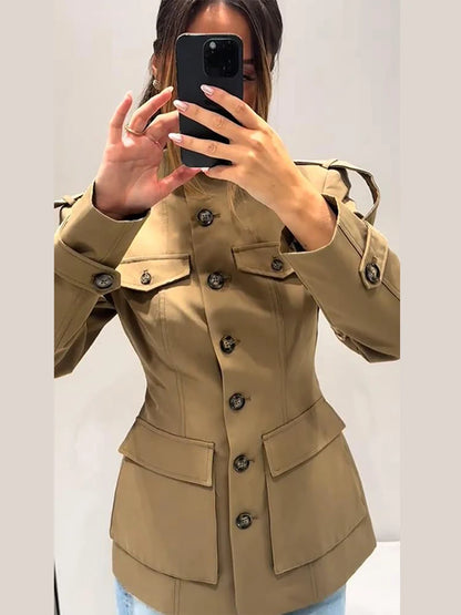 Person wearing a beige trench coat taking a mirror selfie.
