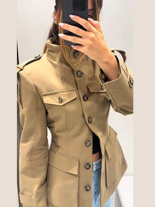 Person wearing a beige trench coat taking a mirror selfie.