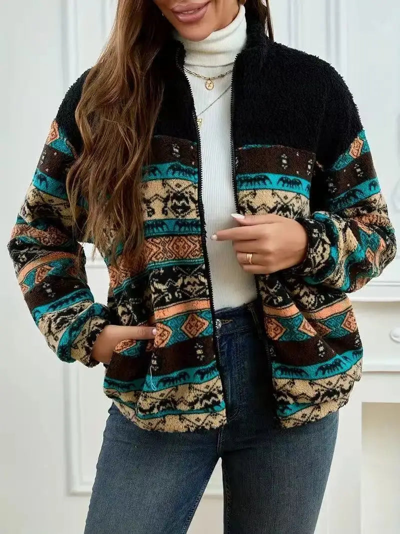 Person wearing a patterned jacket with a white turtleneck and jeans indoors.