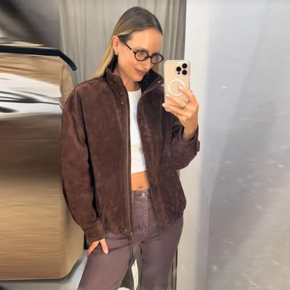 Person taking a mirror selfie wearing a brown jacket and white top.